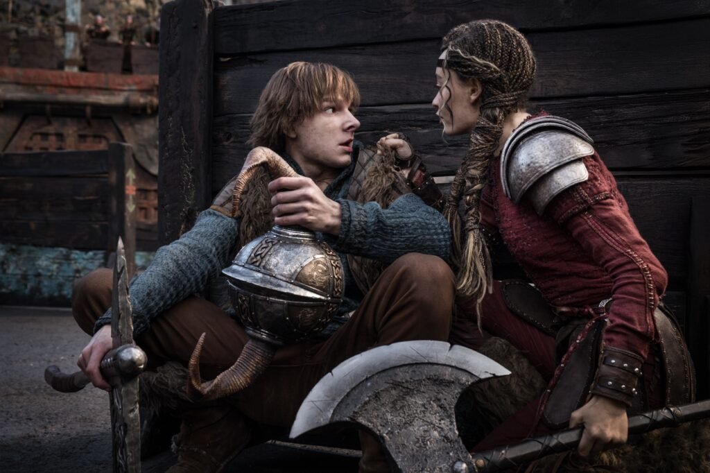 Hiccup and Astrid hiding behind a barrier wall